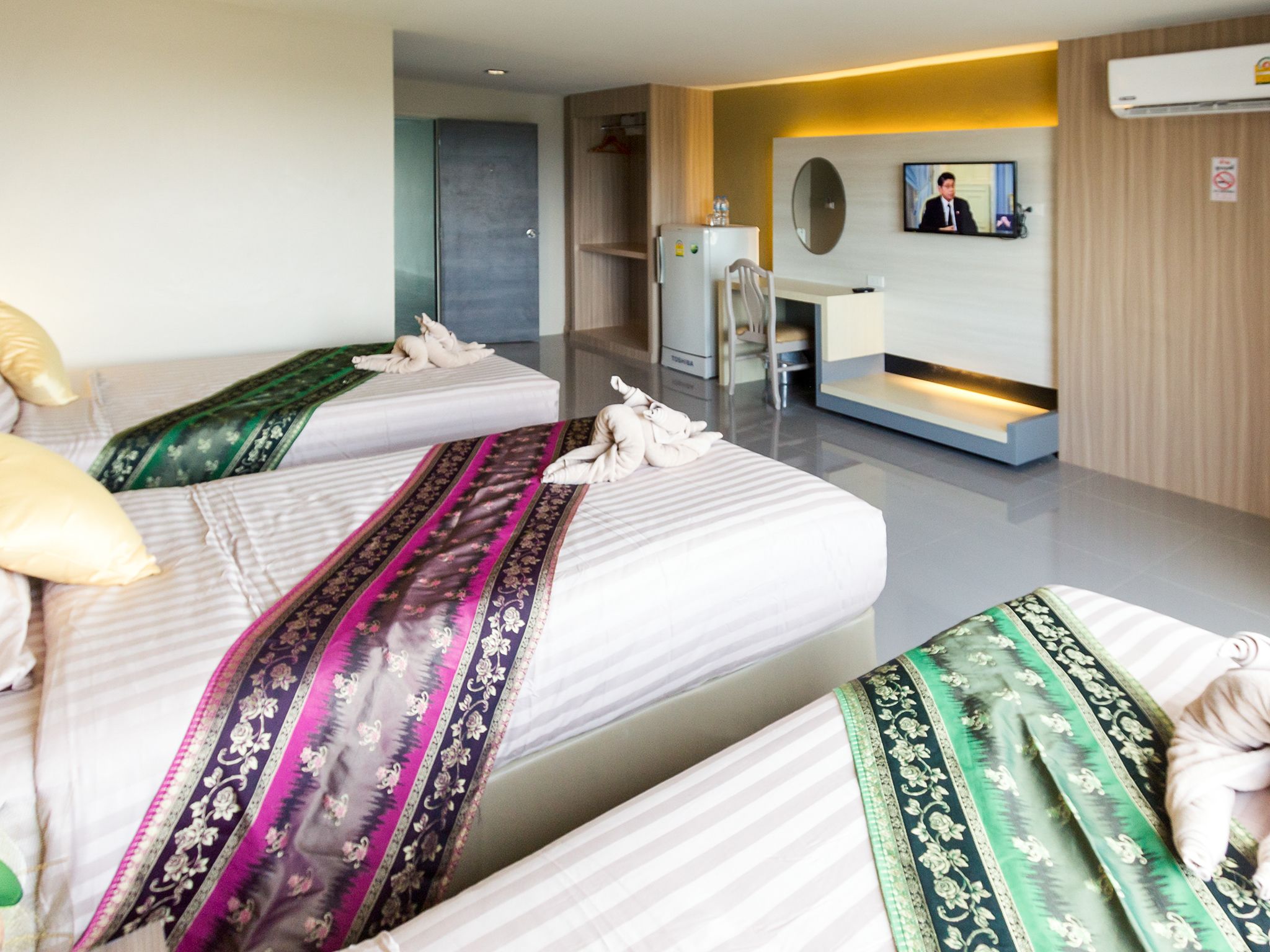 A hotel room with two beds, a desk, a TV, and a minibar.
