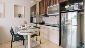 A modern kitchen with a round dining table, black chairs, a refrigerator, microwave, and a stove.