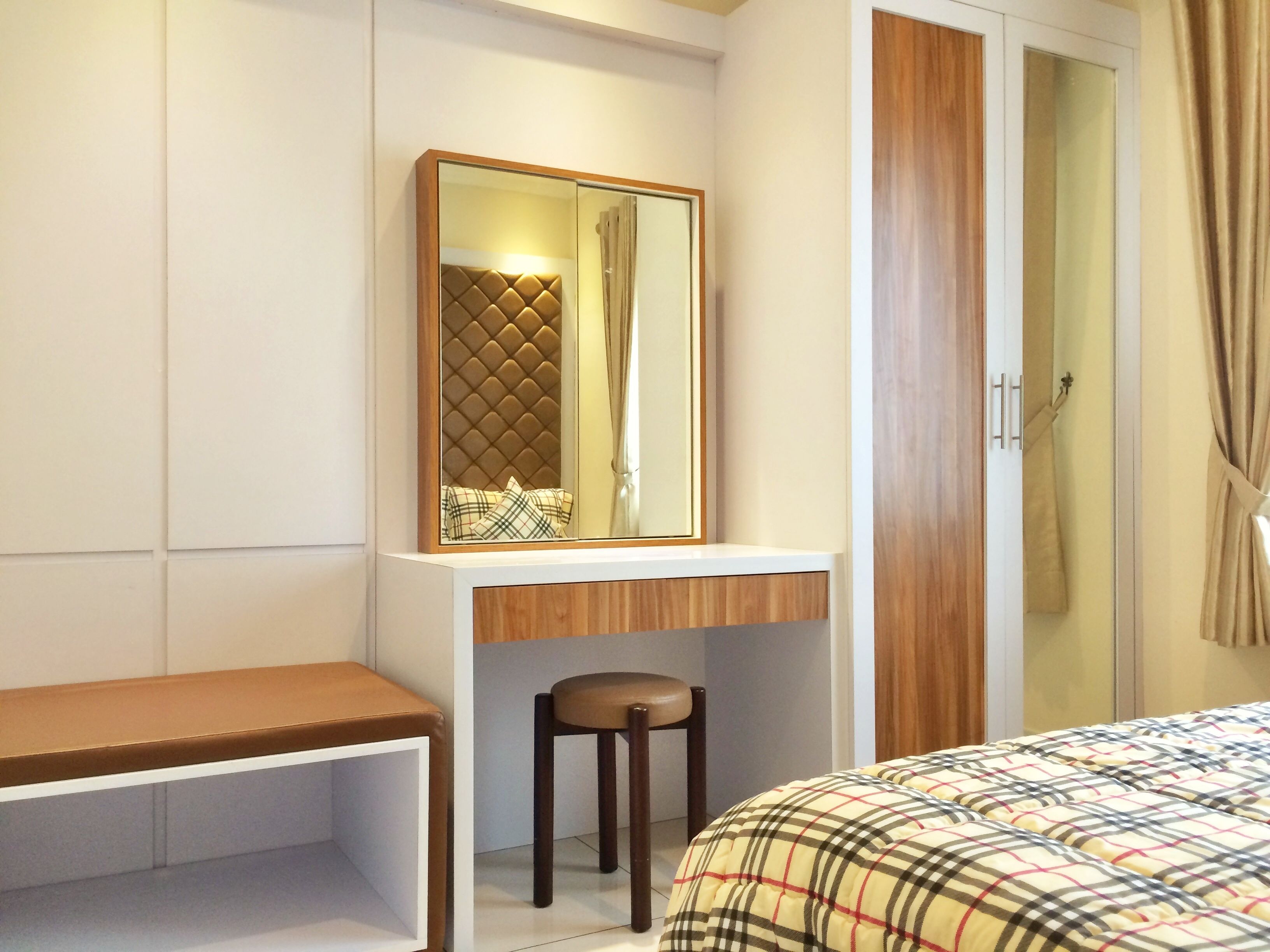 A bedroom with a bed, a desk with a chair, a mirror, and a wardrobe.
