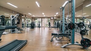 A gym with various exercise equipment, a treadmill, and a mirrored wall.