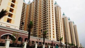A high-rise hotel with multiple floors, featuring balconies and a central courtyard with palm trees.