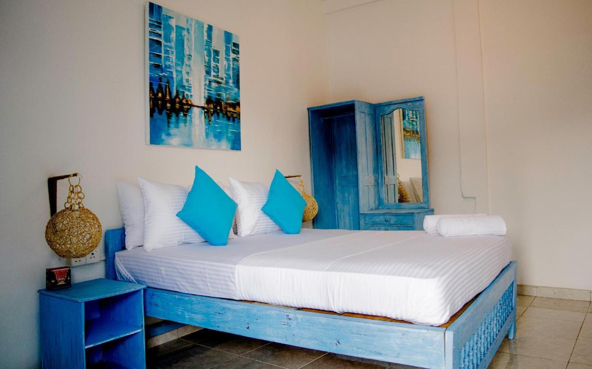 A bedroom with a bed, a nightstand, a wardrobe, and a painting on the wall.