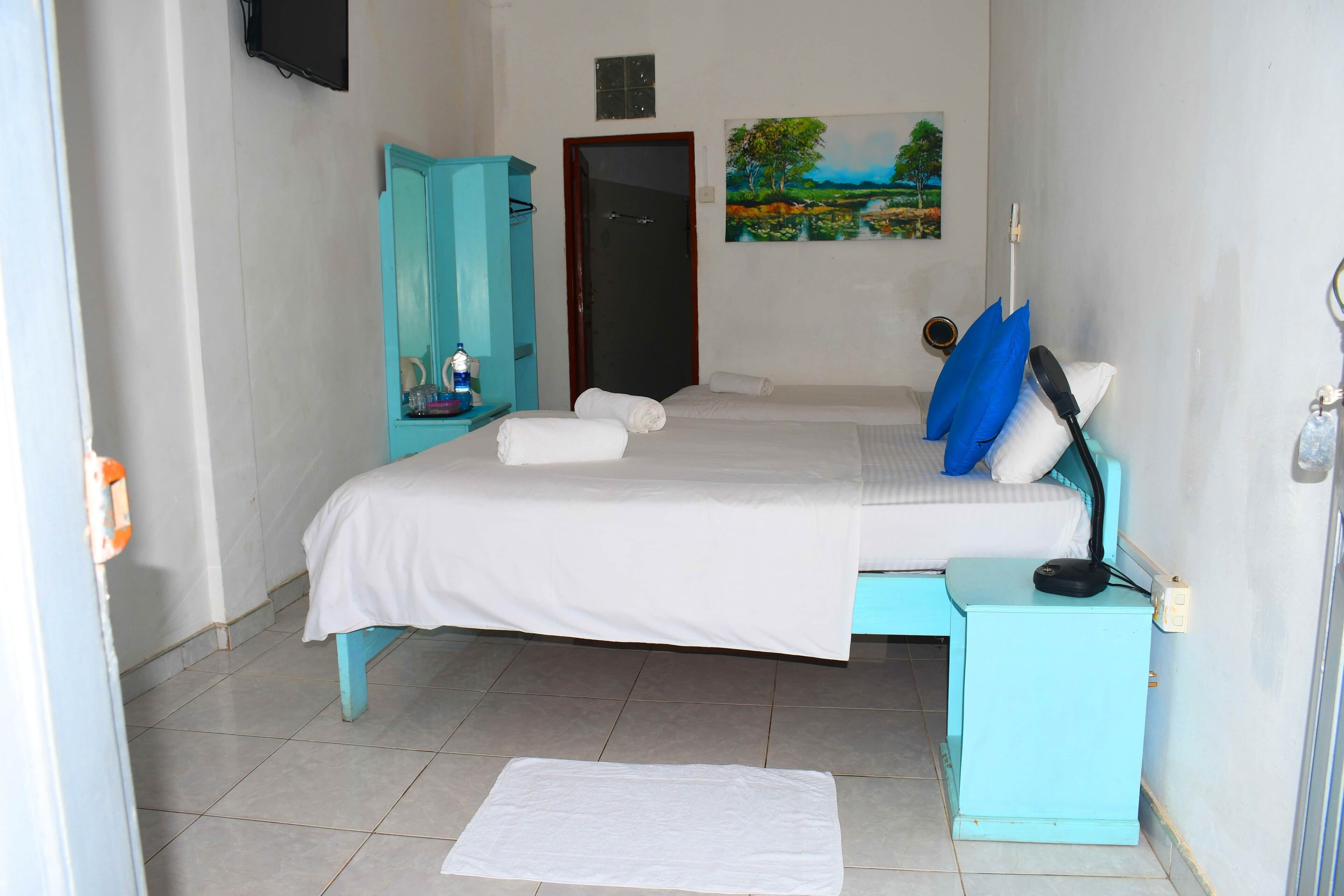 A bedroom with a bed, a nightstand, a wardrobe, and a painting on the wall.