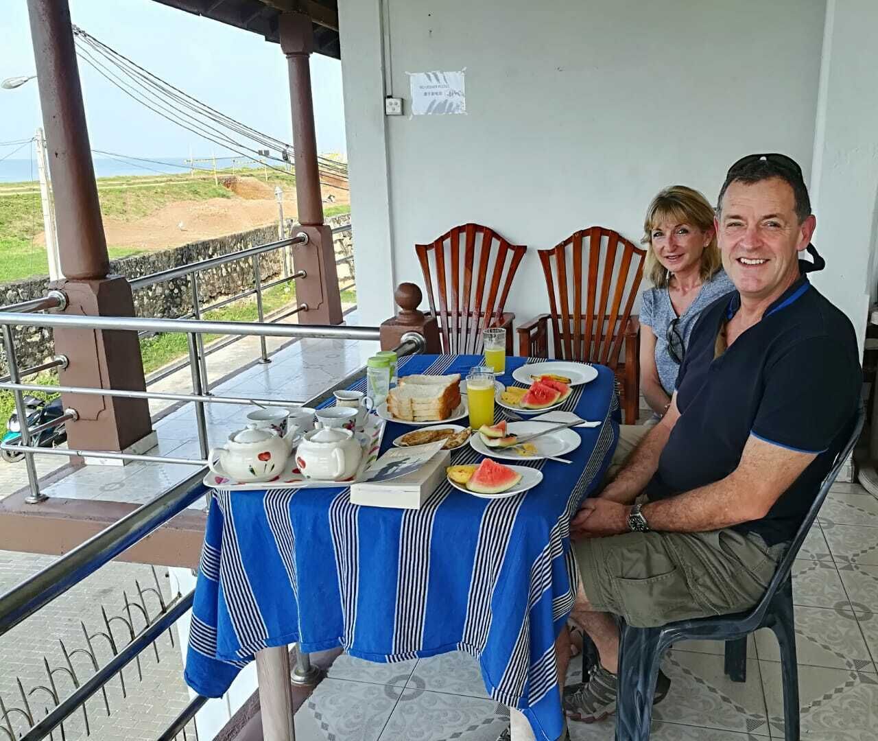 Una mesa de comedor con alimentos para el desayuno, vista al exterior y una barandilla.