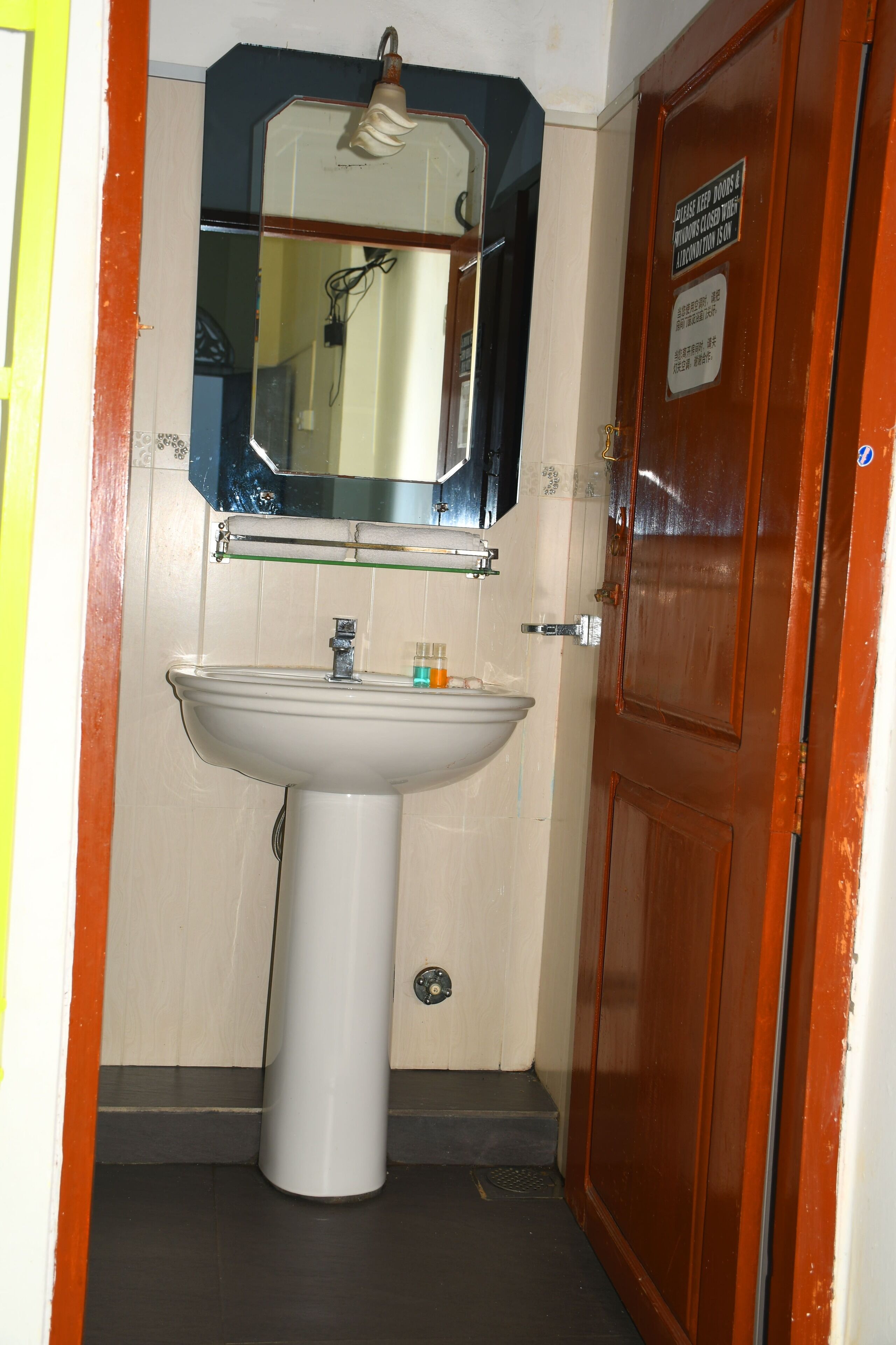 A bathroom with a white sink, a mirror above it, and a wooden door.