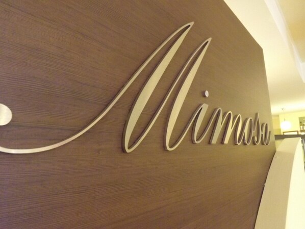 Pared de madeira com o nome "Nimosa" numa fonte cursiva.