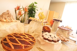 Uma mesa com diversos doces e pastelaria, incluindo uma torta com cobertura em treliça, muffins e um bolo.