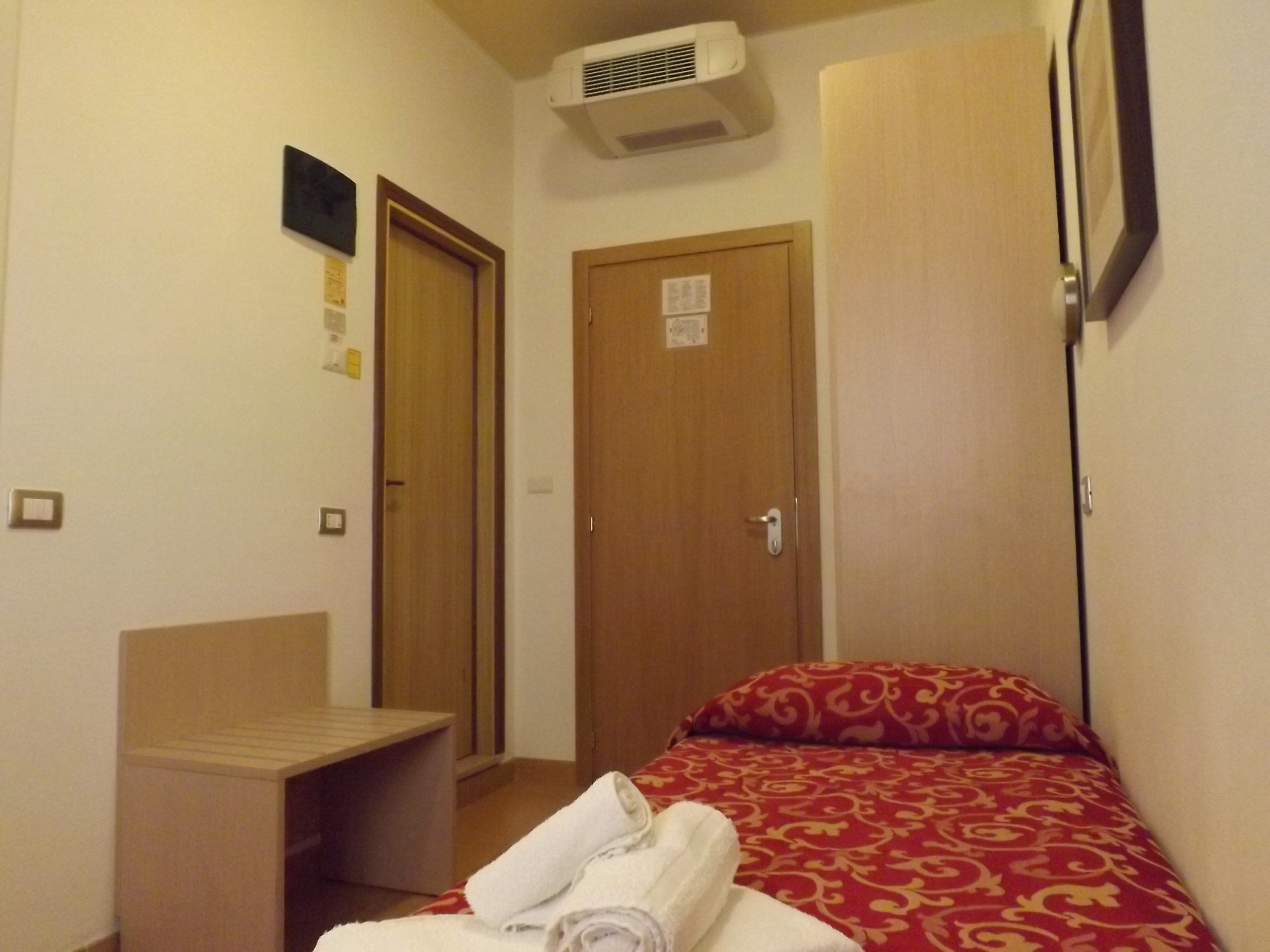 A hotel room with a bed, a desk, and a wardrobe.