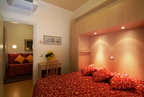 Ein Schlafzimmer mit einem großen Bett, einem Schreibtisch mit Stuhl und einem Spiegel.