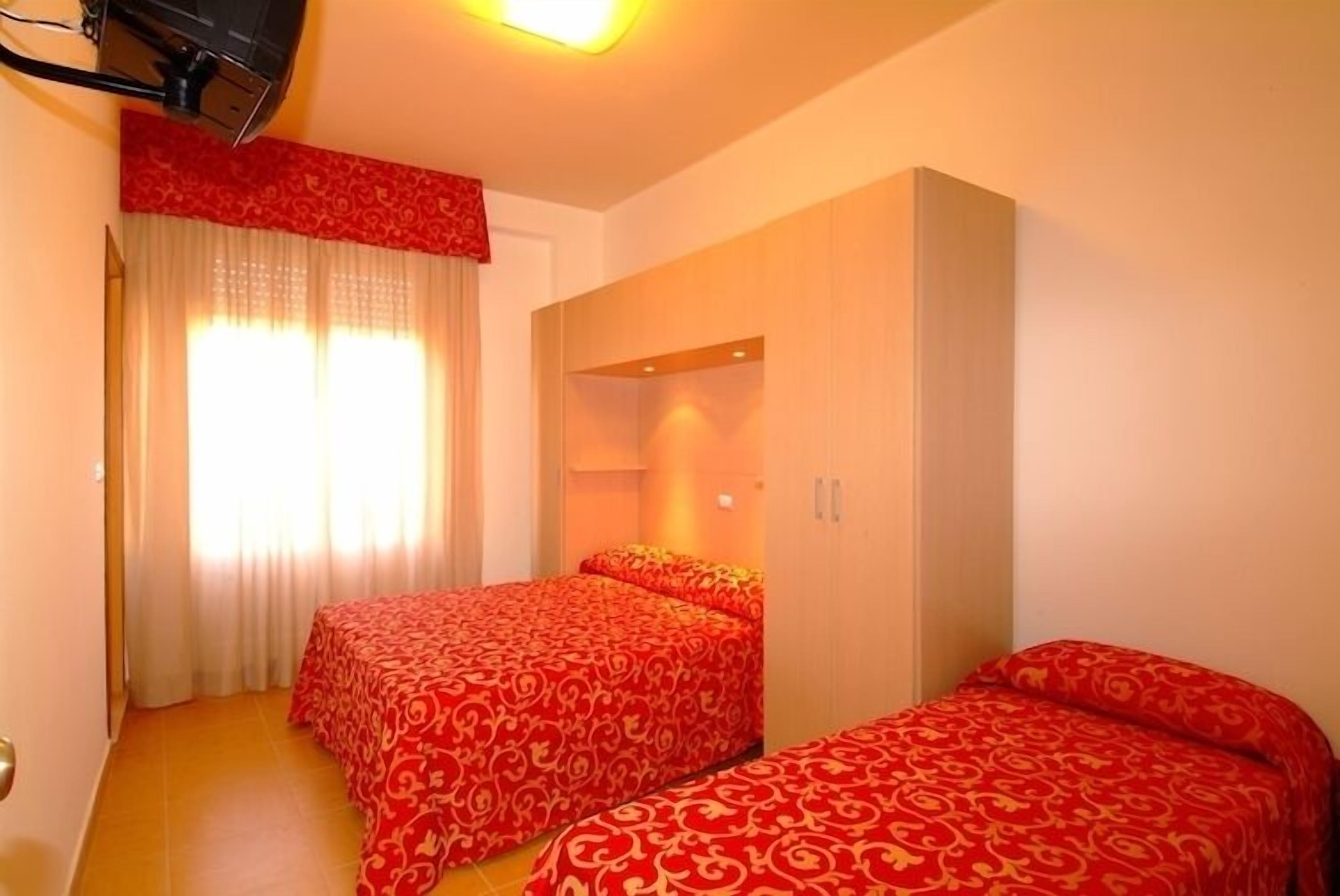 Una habitación de hotel con dos camas, un televisor y un armario.