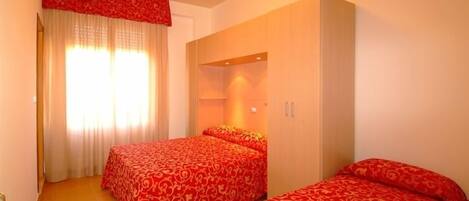 Una habitación de hotel con dos camas, un televisor y un armario.