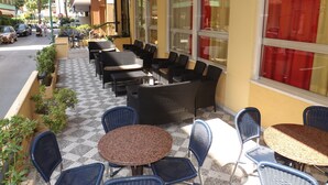 Un espacio al aire libre con mobiliario de mimbre y piso a cuadros.