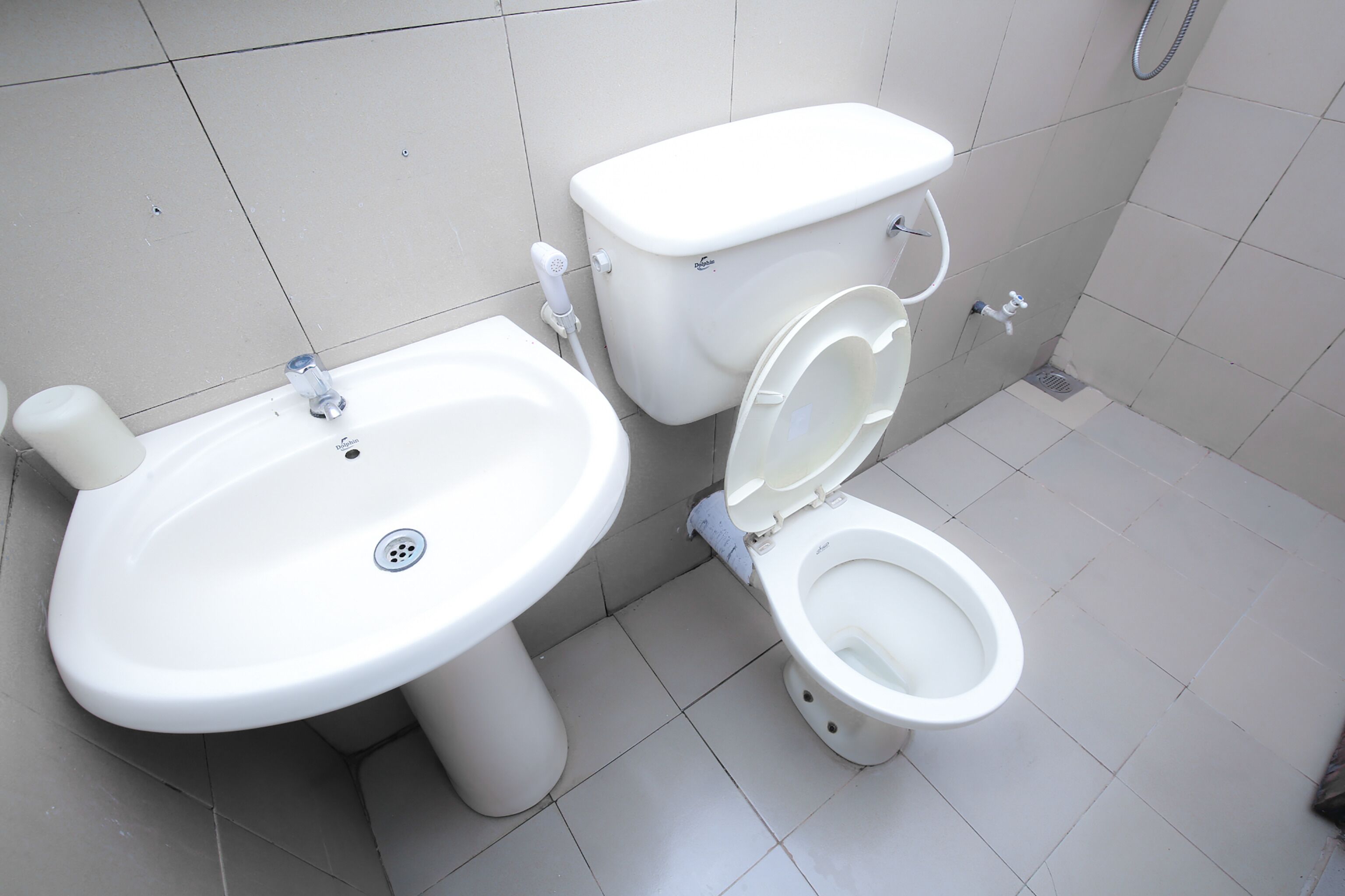 Un baño con lavamanos, inodoro y ducha blancos.