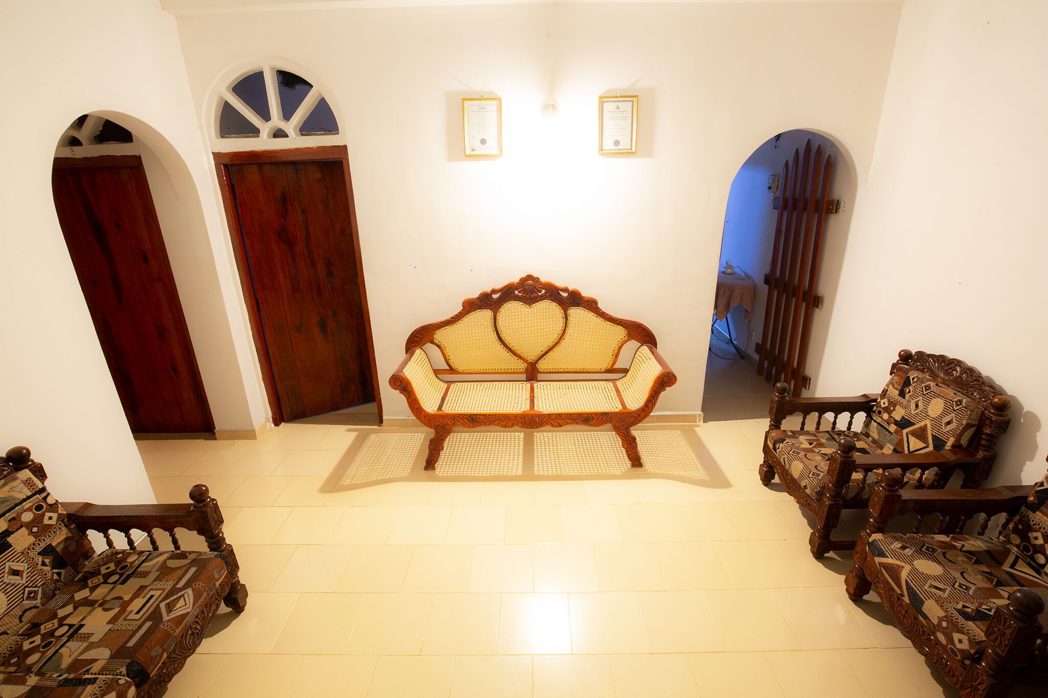 A room with a central sofa, two armchairs, and a wooden door.