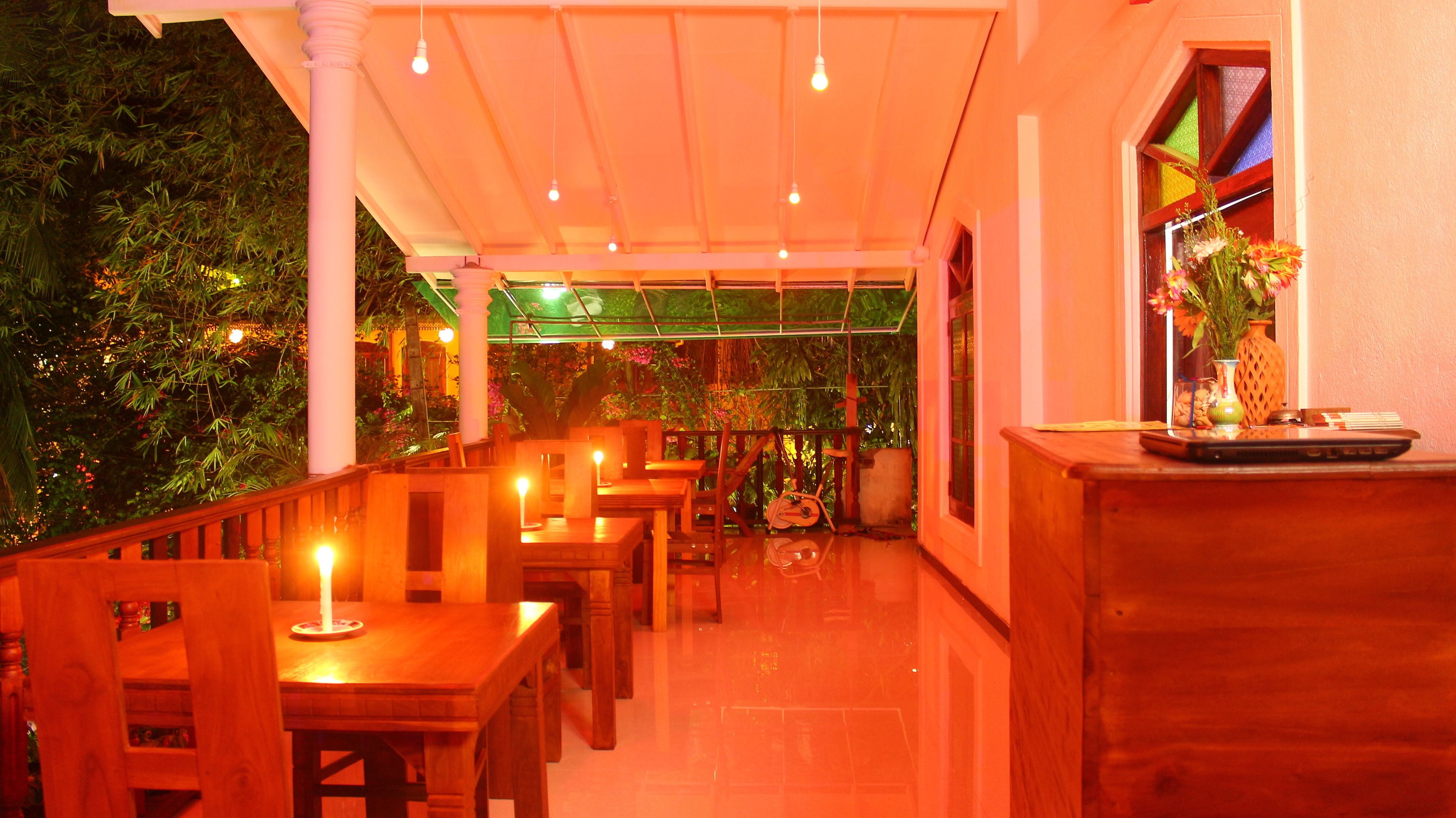 Un comedor interior con mesas y sillas de madera, una barra con un florero y vistas a zonas verdes al exterior.