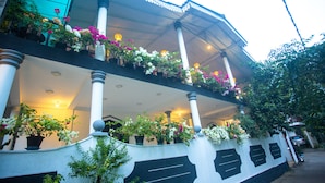 A building with a balcony adorned with potted plants and flowers, columns, and a covered upper level. - La Villa Guest House (Unawatuna)