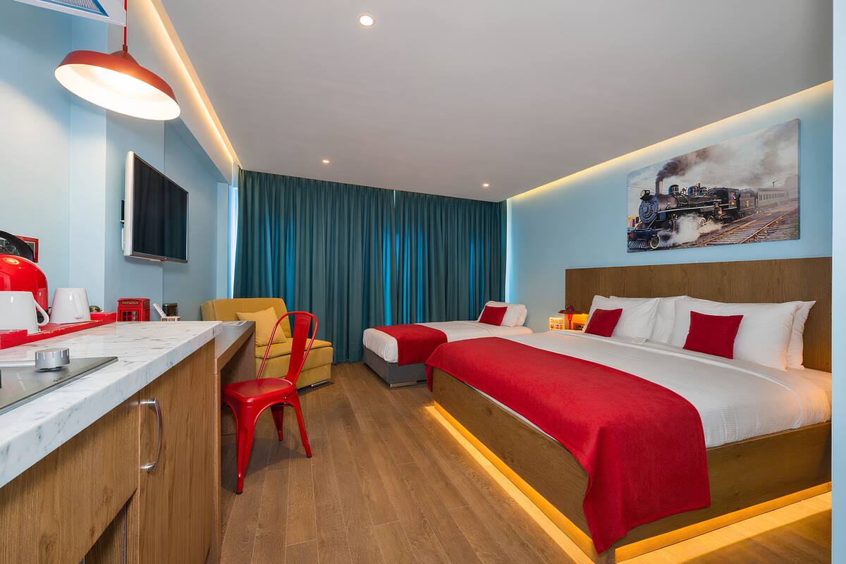 A hotel room with a bed, a desk, a chair, a TV, and a painting on the wall.