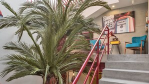 Una escalera con barandas rojas, una palmera y una radio antigua.