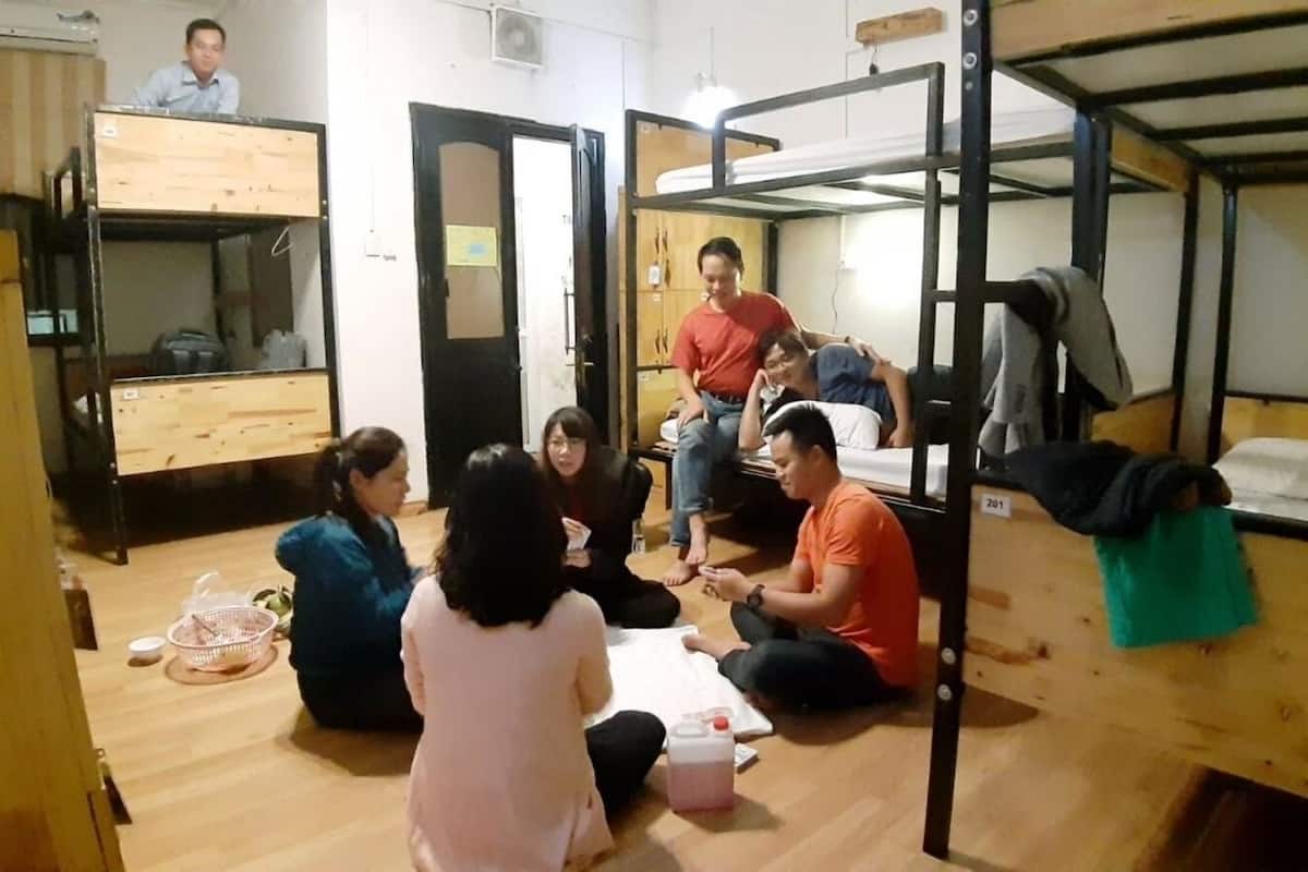 A dormitory room with bunk beds, a wooden floor, and a door.