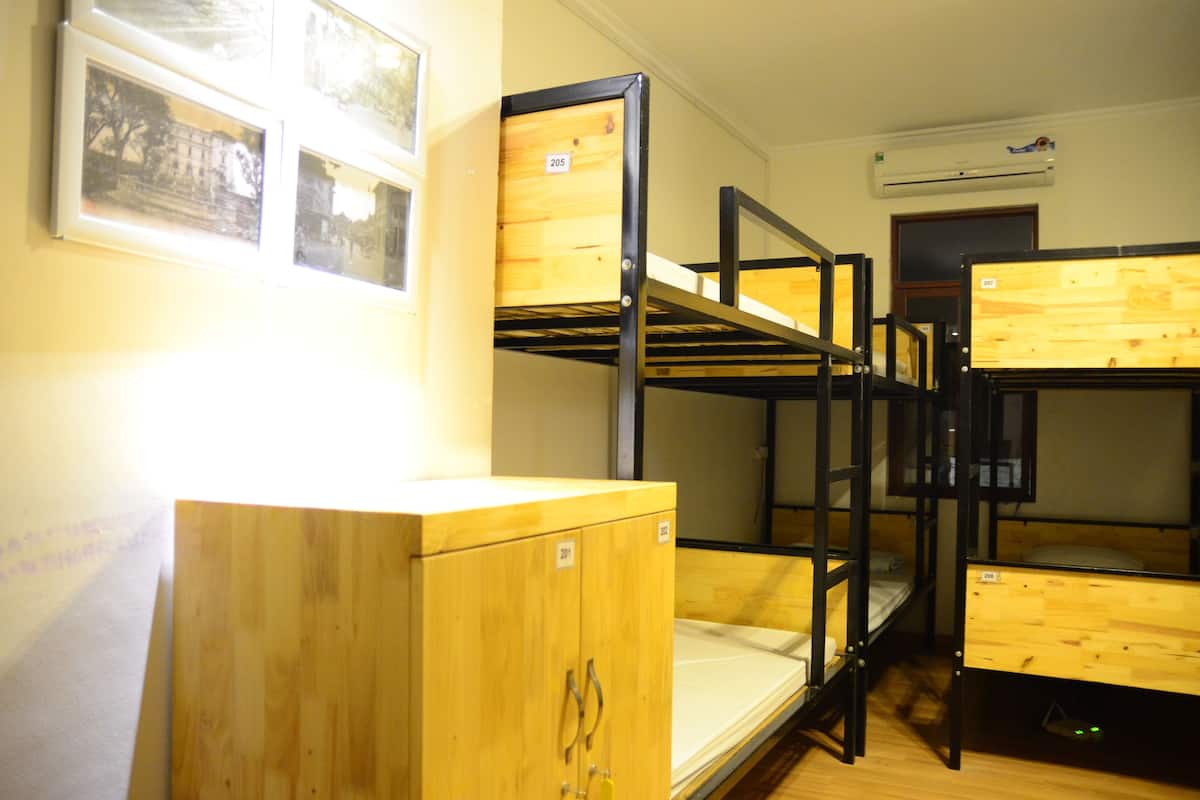 A dormitory room with bunk beds, wooden cabinets, and framed pictures on the wall.