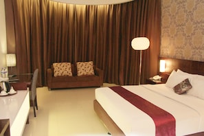 Ein Hotelzimmer mit einem großen Bett, einer Couch, einem Schreibtisch und einer Lampe.