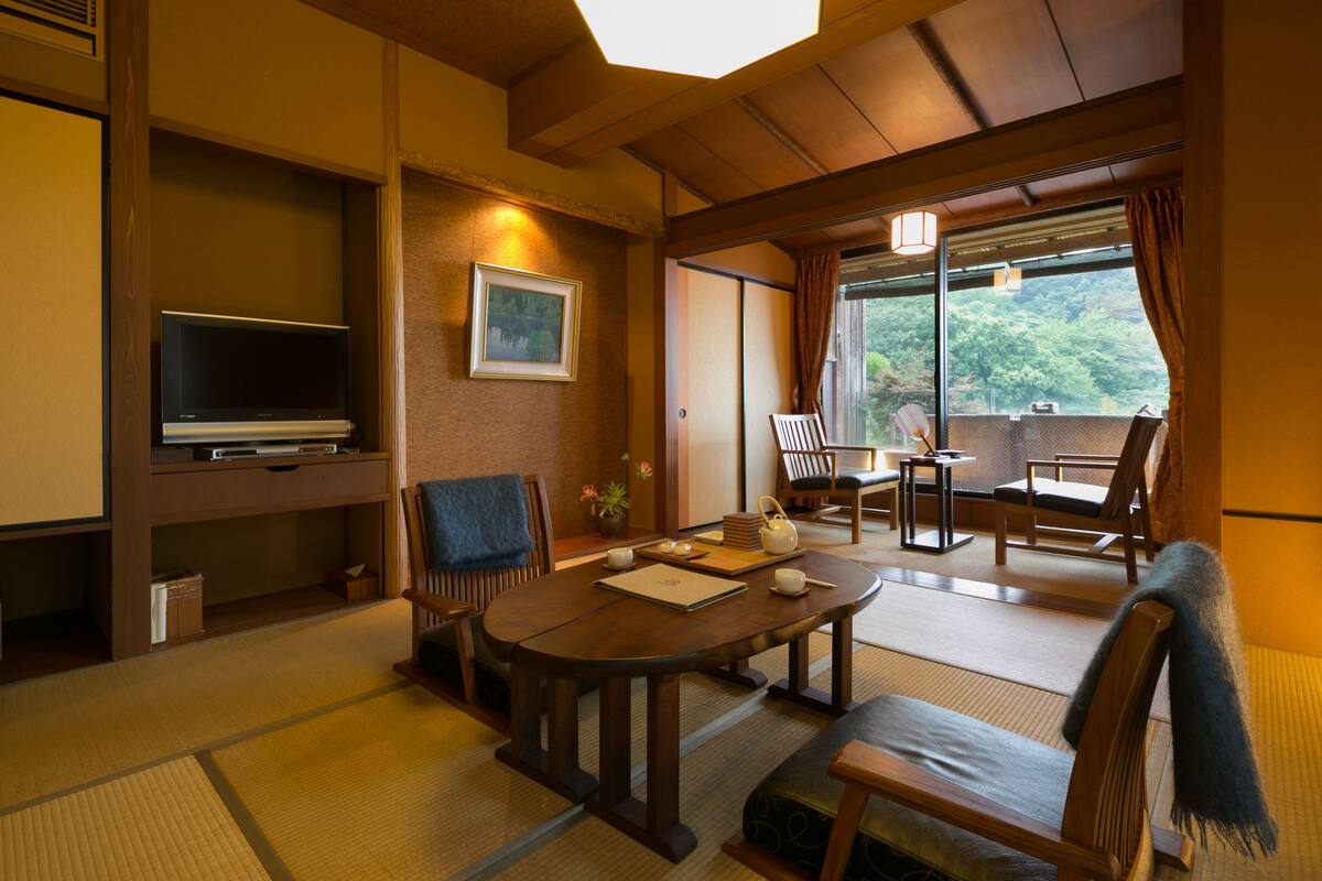 A traditional Japanese room with tatami flooring, a low table, and a television.
