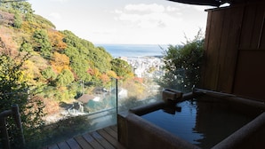 A hot spring area with a wooden deck and a glass balustrade overlooking a city and autumn foliage. - wa-tei Kazekomichi (Atami)