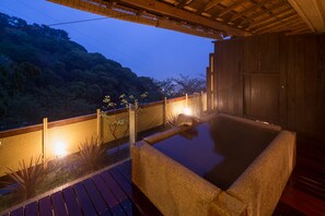 A hot spring bath area with a wooden deck, stone seating, and a view of a forested hillside. - wa-tei Kazekomichi (Atami)