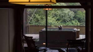 A room with a sliding glass door leading to an outdoor area with a hot tub and a wooden deck. - wa-tei Kazekomichi (Atami)