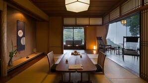 A traditional Japanese-style room with tatami flooring, a low table with cushions, and a view of the outdoors. - wa-tei Kazekomichi (Atami)