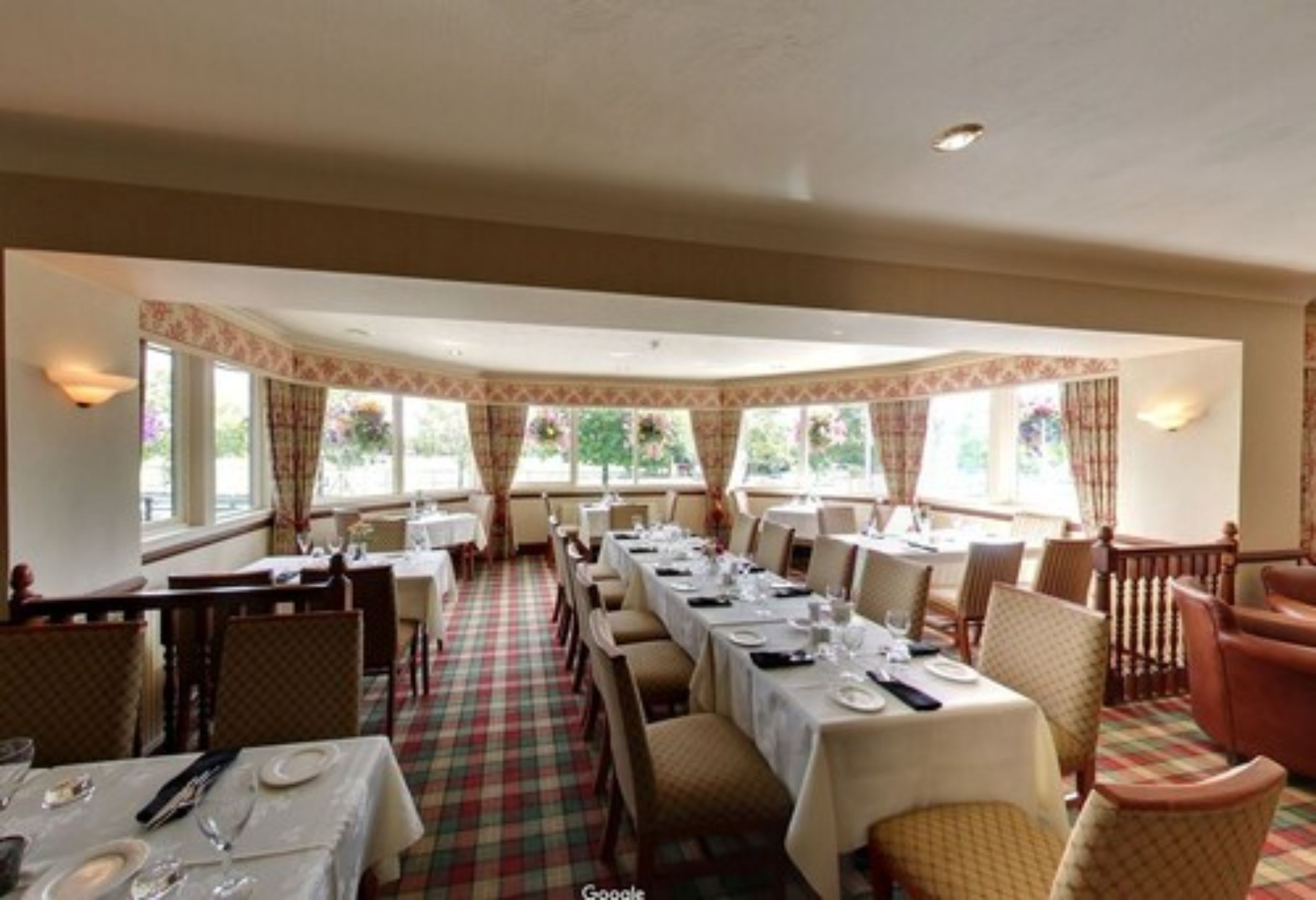 A restaurant with a long dining table set for a meal, surrounded by chairs.
