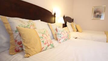 A hotel room with a wooden headboard, floral-patterned pillows, and a bedside lamp.
