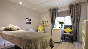 Un dormitorio con cama, silla, escritorio y ventana con cortinas.
