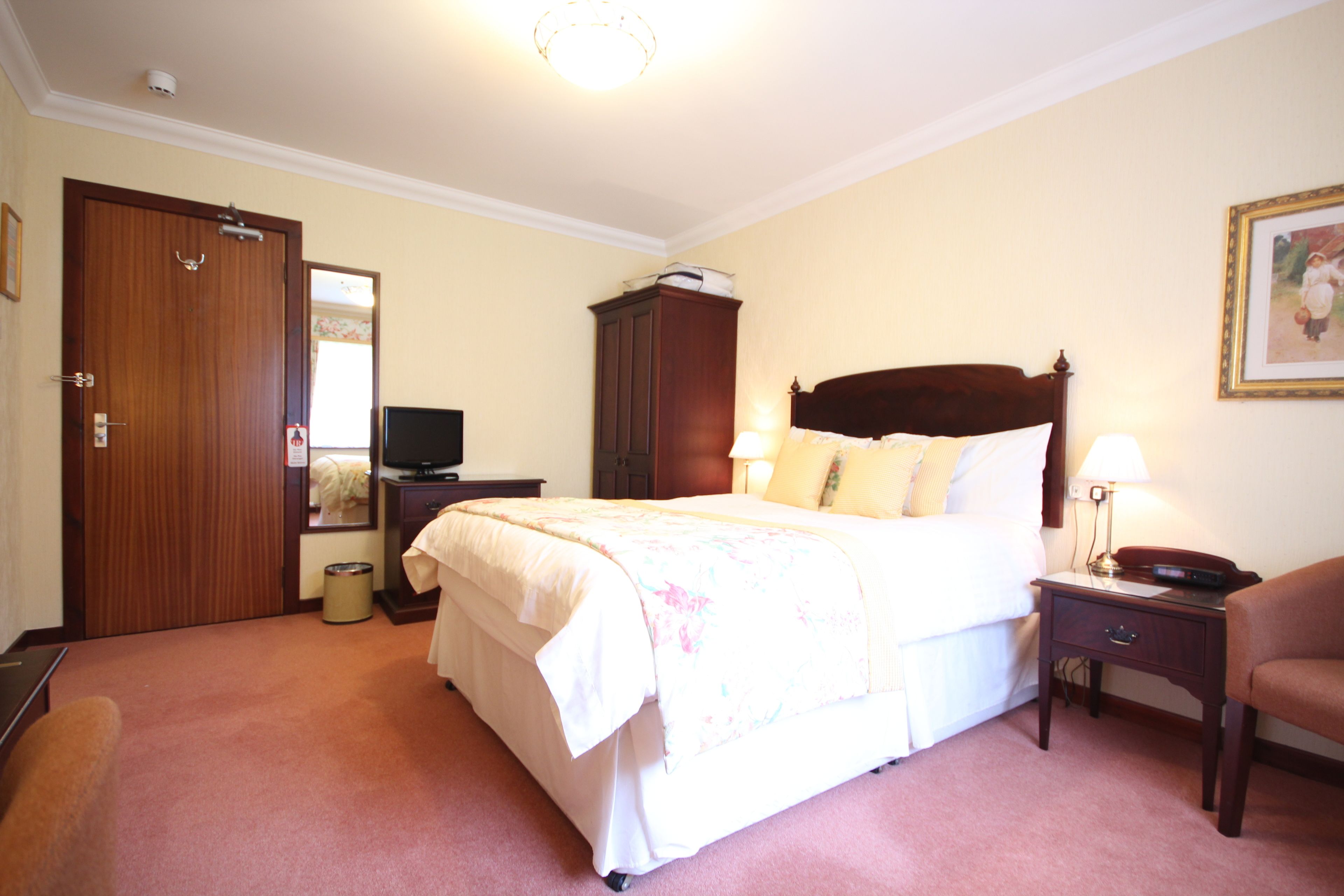 A hotel room with a bed, a television, a wardrobe, a desk, and a chair.