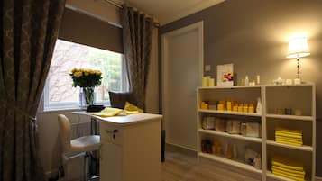 A bathroom with a shower chair, a vanity with toiletries, and a window with curtains.