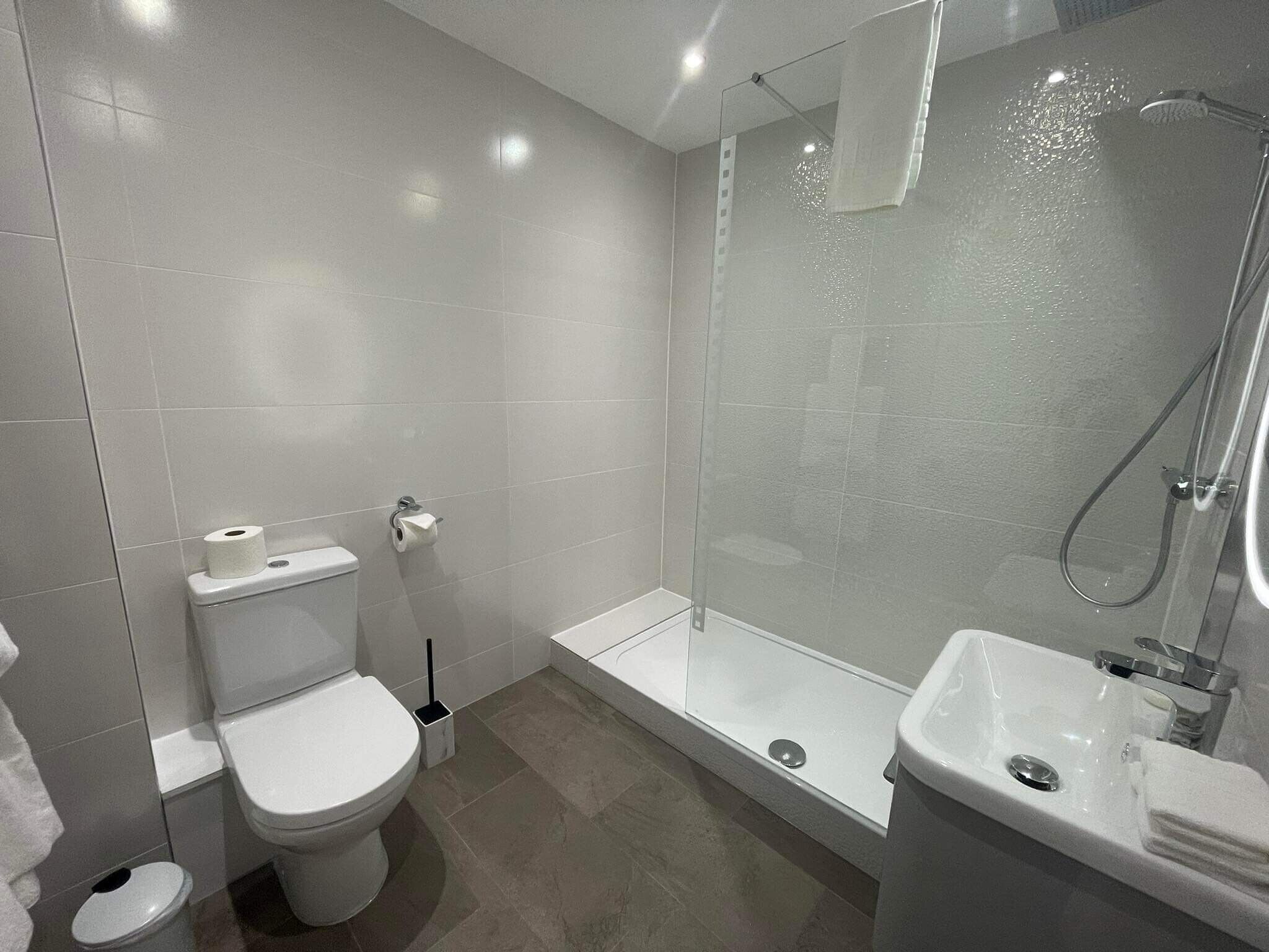 A modern bathroom with a toilet, a glass-enclosed shower, and a sink.