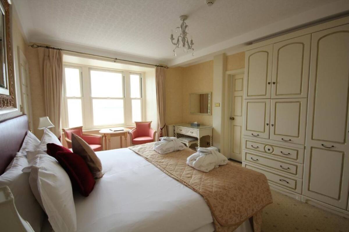 Quarto de hotel com uma cama grande, uma escrivaninha, uma cadeira e um guarda-roupa.