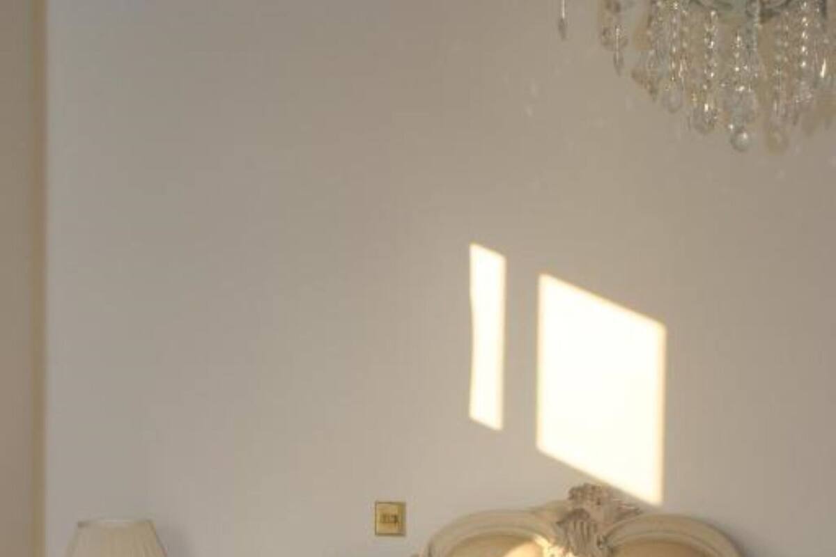 Quarto bem iluminado com cama grande, cabeceira elaborada e almofadas decorativas.