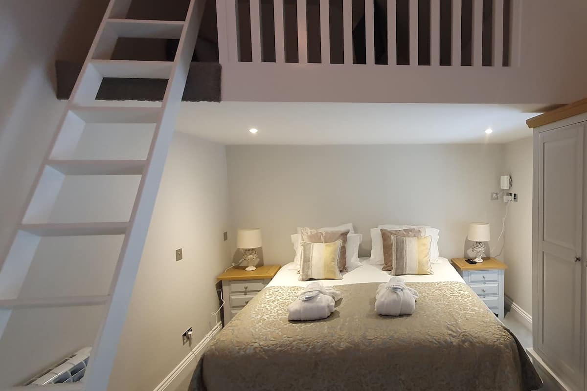 Um quarto com cama, mesas de cabeceira, luminárias e um guarda-roupa.