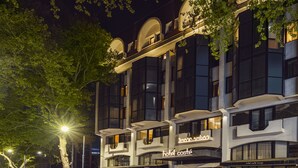 Et hotel med en moderne facade, flere balkoner og udendørs siddeområder.