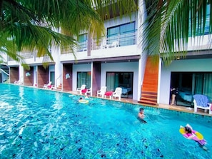 A swimming pool with clear blue water, surrounded by lounge chairs and palm trees. - Rimnatee Resort Trang (Trang)