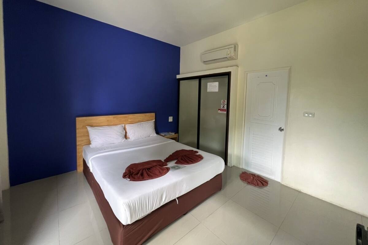 A hotel room with a bed, a wardrobe, a door, and a wall-mounted air conditioner.
