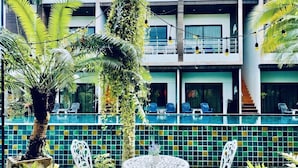 A poolside area with a tiled pool, white outdoor furniture, and lush greenery. - Rimnatee Resort Trang (Trang)