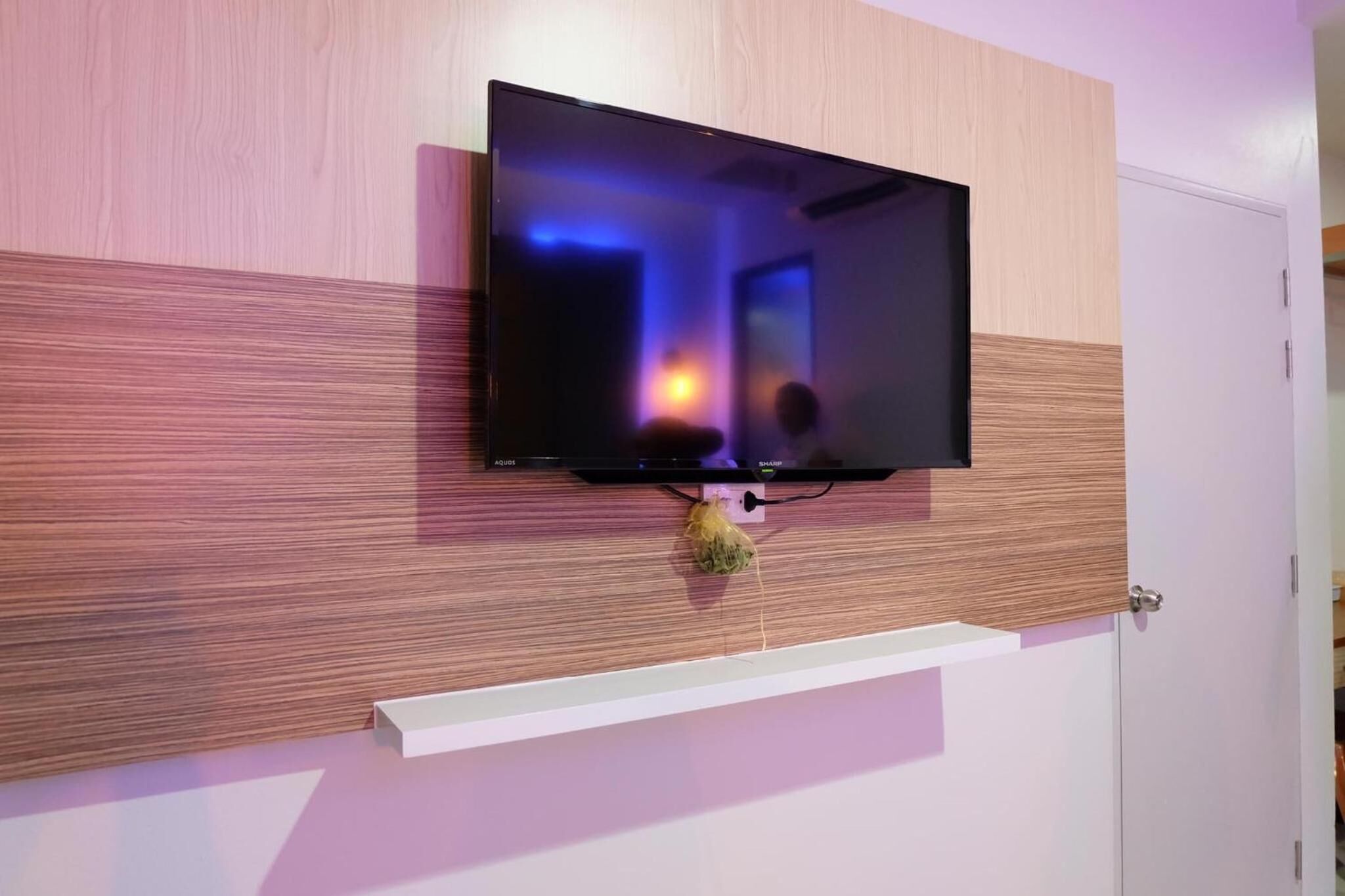 A flat-screen TV mounted on a wall with a wooden panel design.