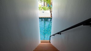 A staircase leading to a pool with blue tiles and a palm tree outside. - Rimnatee Resort Trang (Trang)
