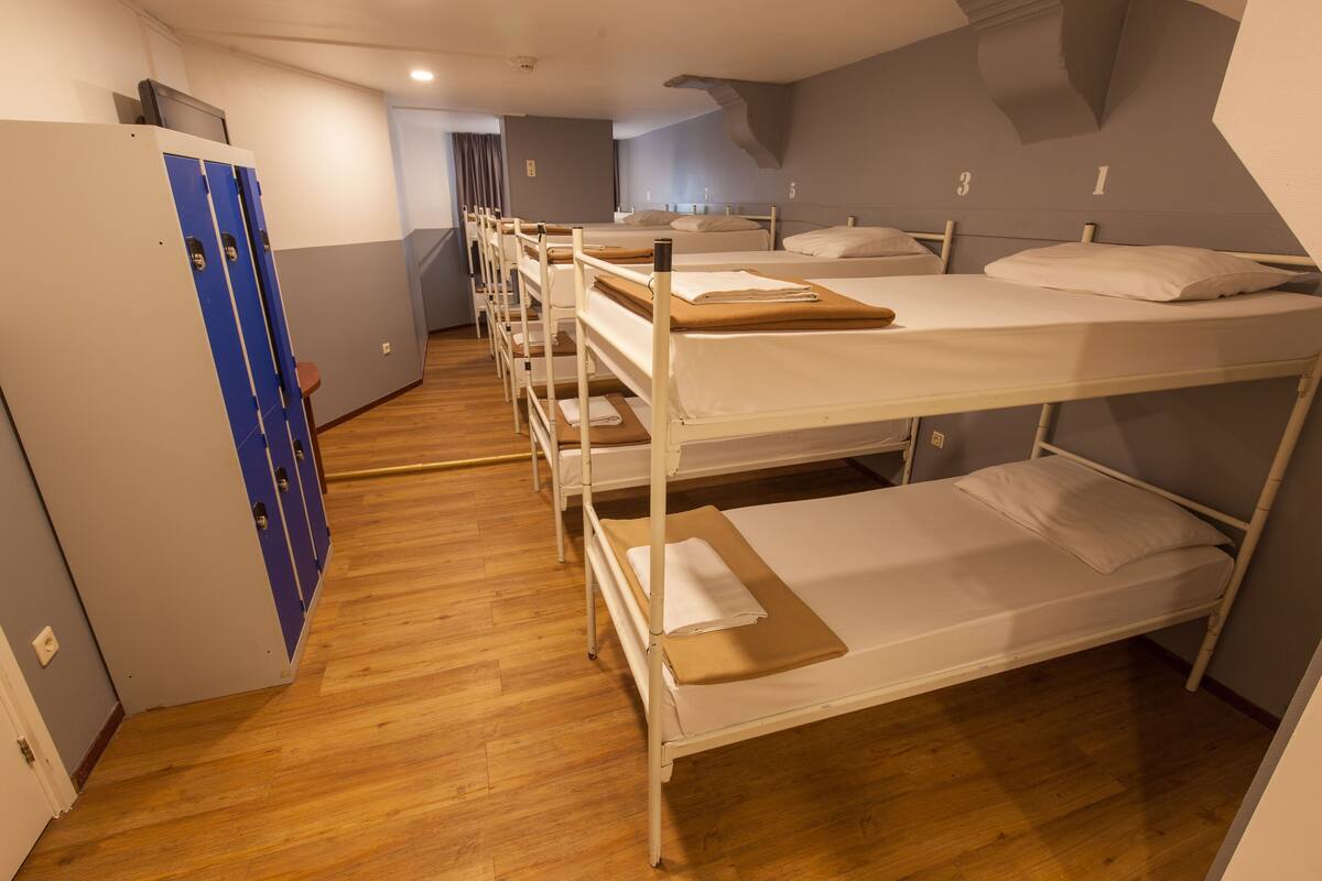 Un dormitorio con literas, suelo de madera y taquillas azules.