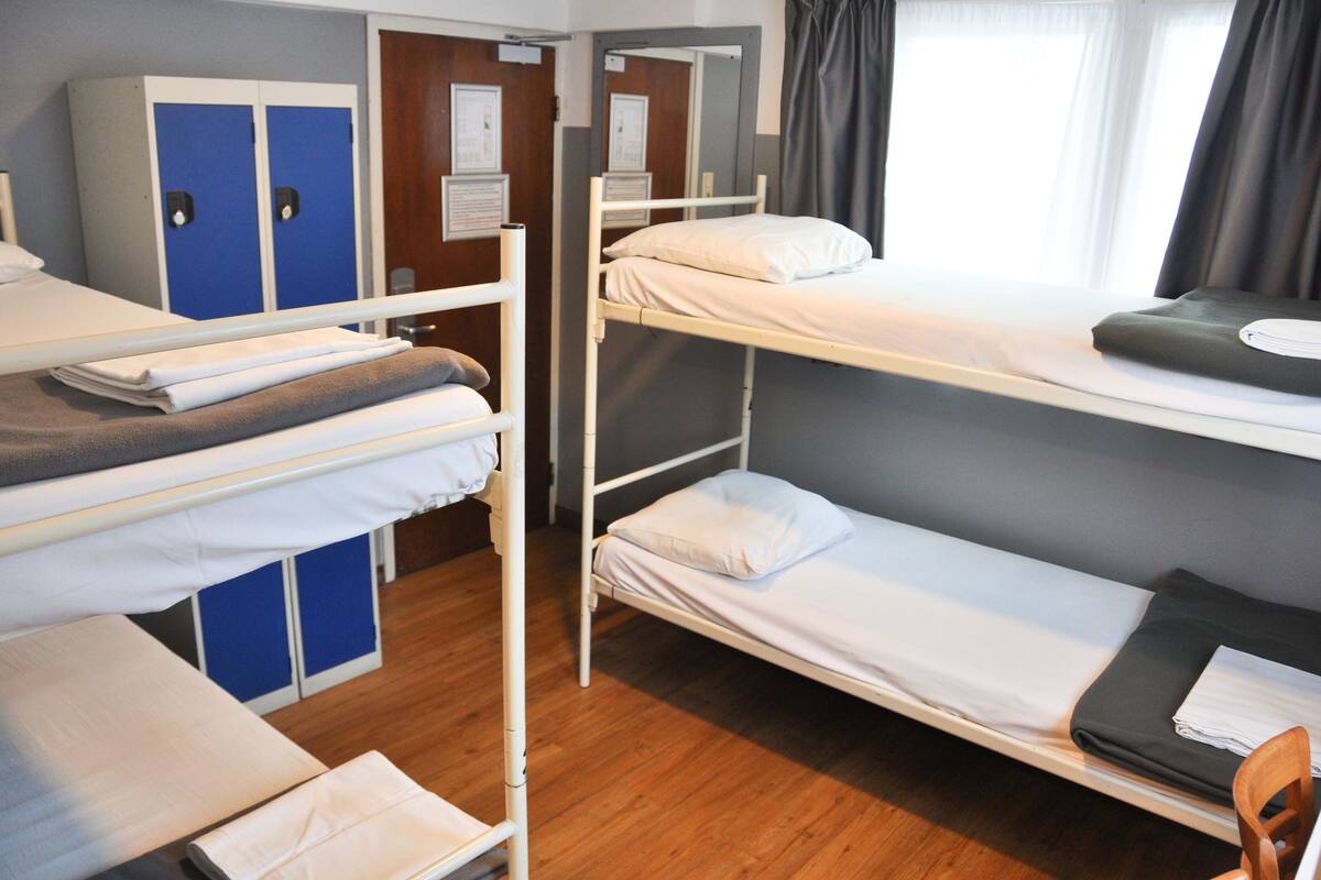 Un dormitorio con literas, un armario y una ventana con cortinas.