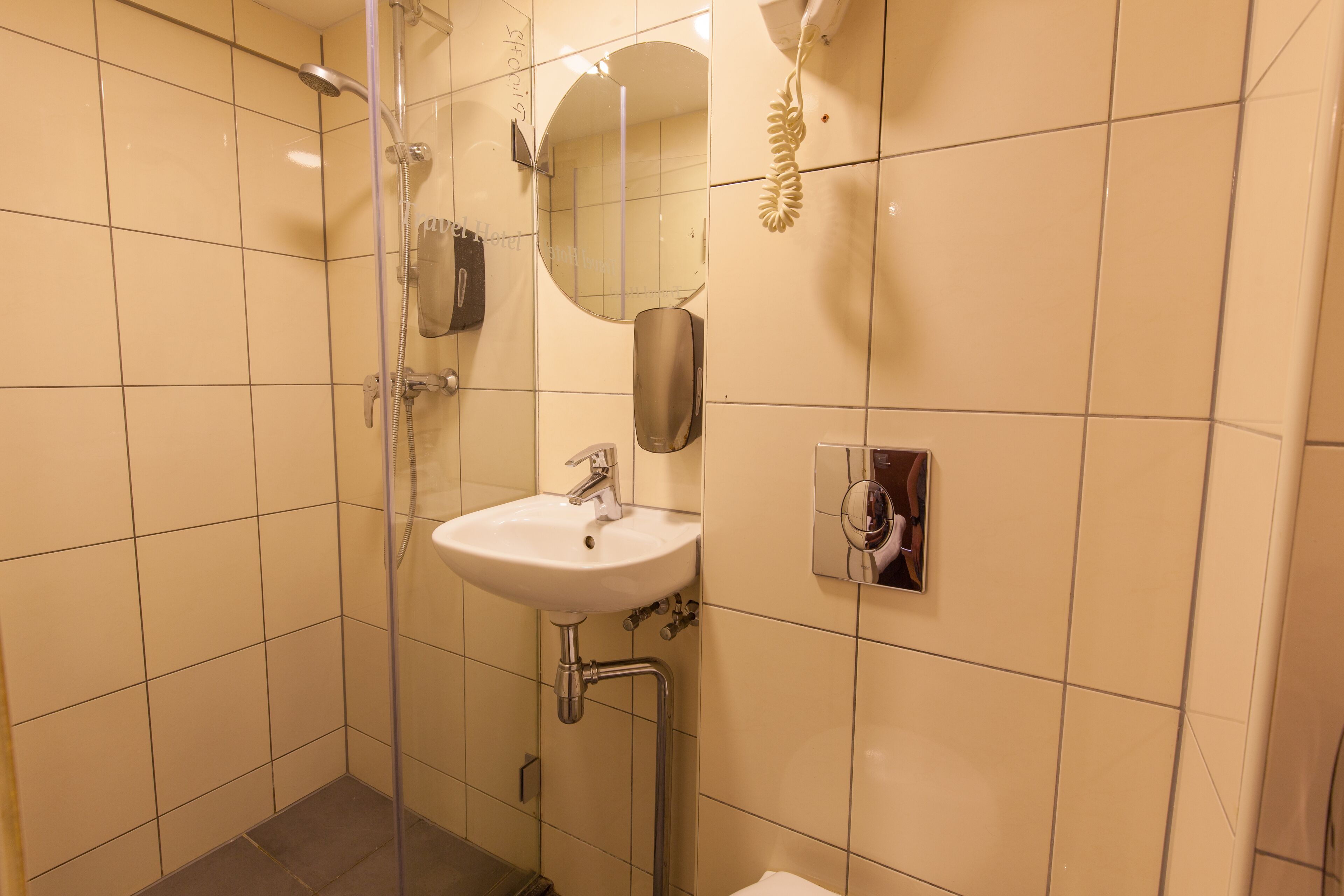 A bathroom with a glass-enclosed shower, a sink, and a mirror.