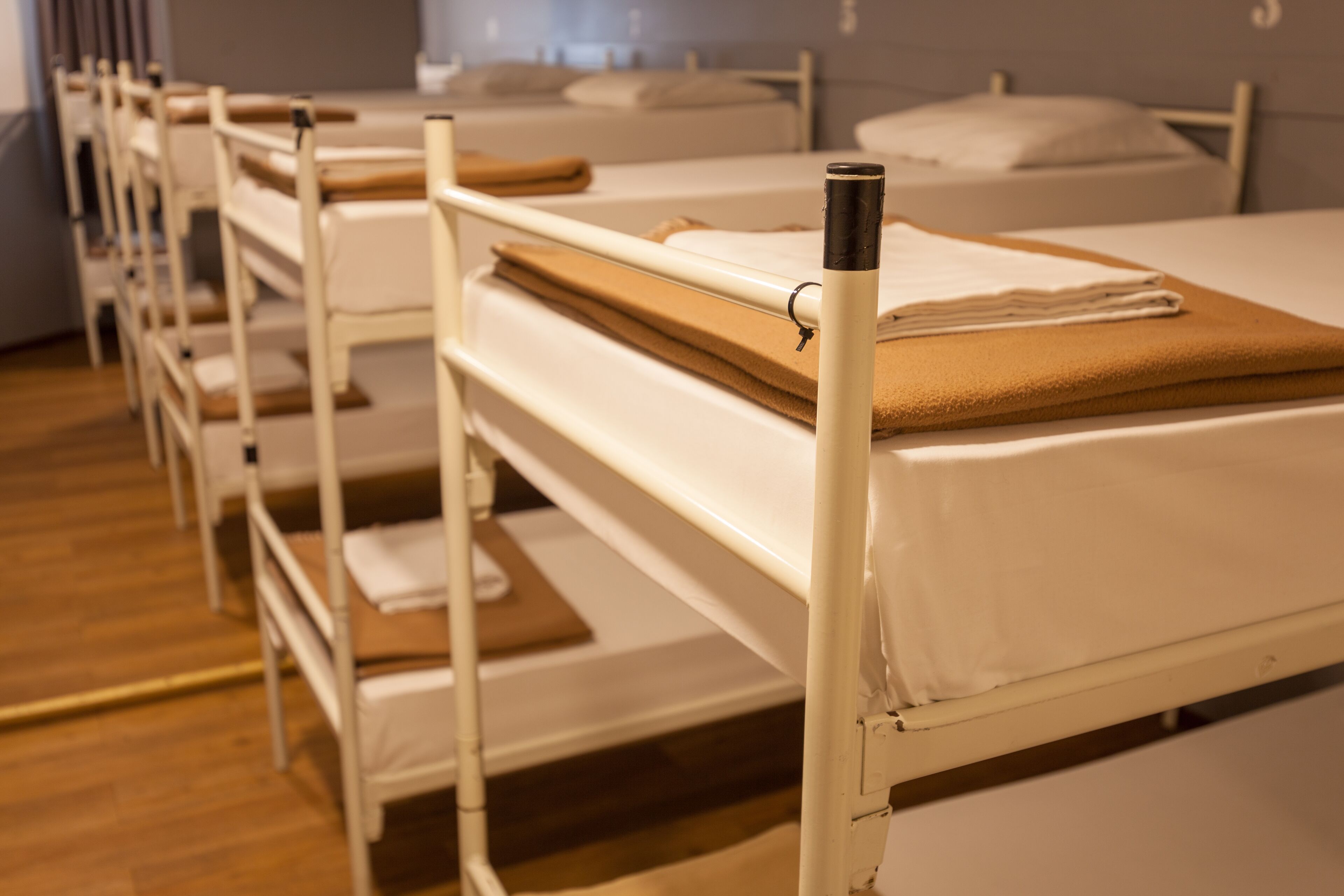 A row of bunk beds with white frames and beige bedding.