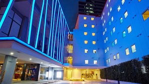 A modern hotel with a prominent entrance, multiple floors, and a well-lit facade.